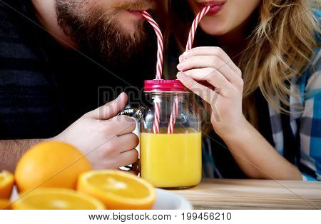 Young people drinking orange juice in kitchen.