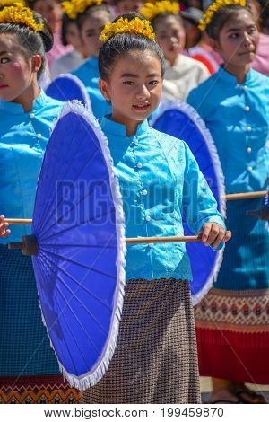 CHIANGMAI THAILAND - JANUARY 25 2015: Indigenous little girl with traditional costume holding blue umbrella and dancing in traditional style in parade of 22nd Traditional Skirt Fabric and The Indigenous Product and Culture Festival in Mae Chaem Chiangmai