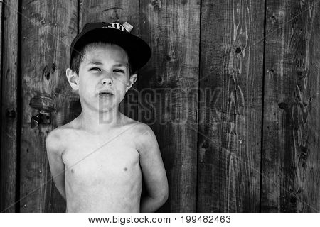 a boy stands near wooden wall in the summer
