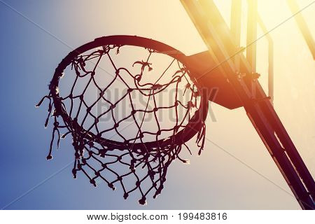 Basketball hoop on amateur outdoor basketball court for streetball against strong summer sunlight