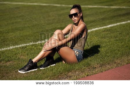 Beautiful young sexy woman in jeans shorts at summer on football stadium
