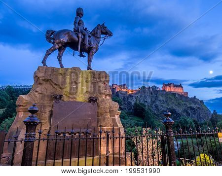 Royal Scots Greys Monument with Edinburgh Castle in the background at night from Princes Street.