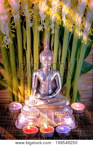 Selective Focus Of Buddha Statue With Blurred Burning Candle Light In Soft  Light And White Flower O