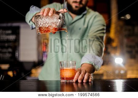close up of bartender pouring the cocktail into the glass