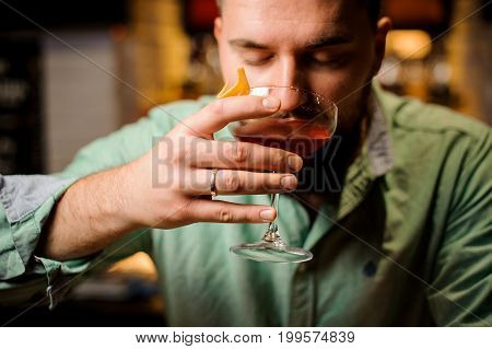 bartender is holdind cocktail with closed eyes