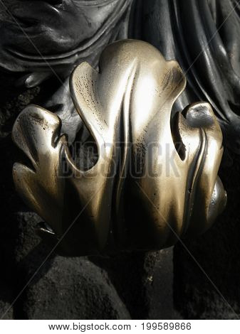 decorative ornate old brass door handle with stylised leaf design in cold and black tones