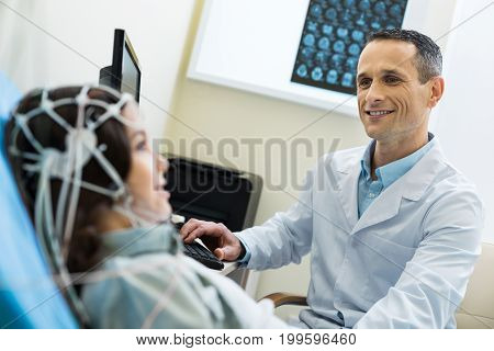 Precise data. The focus being on a charming pleasant medical specialist recording electroencephalographic waves of the brain of a beautiful young woman