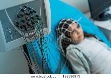 Medical examination. The focus being on the wires connected to the electroencephalograph recording the brain waves of pretty little girl undergoing electroencephalography