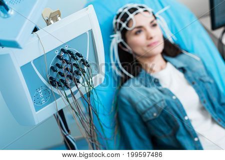 Top-notch equipment. The focus being on a modern electroencephalograph being connected to the head of a charming young woman