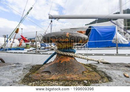 Old harbor mooring with ropes in the background of the summer marina on a sunny day.