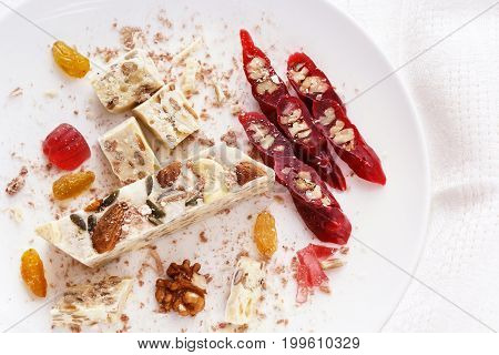 Halva, walnut, churchchel, raisins and marmalade on a white plate. Eastern sweets. Soft light. High key
