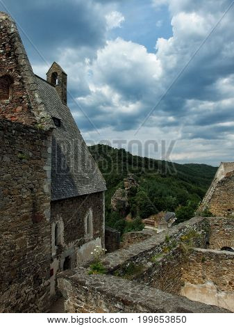 Medieval fortress on a hill under heavy clouds.