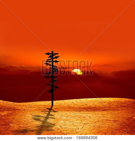 conceptual image of silhouetted directional sign on cracked dry landscape over sunset 