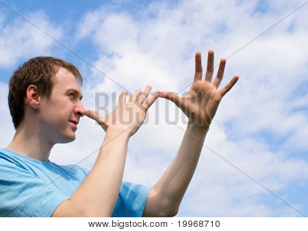 Der junge Mann spielt über und wriggles gegen den blauen Himmel