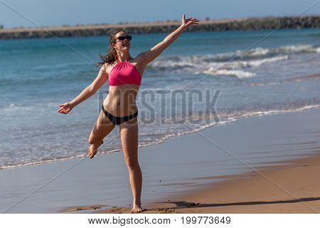 Teenager girl throwing frisby on beach ocean waterline.