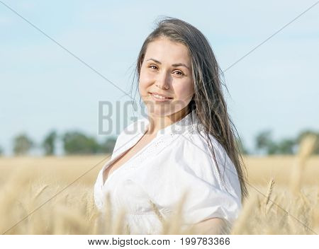 Pretty female smiling in wheat field at warm sunner day