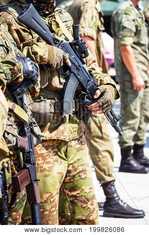 Soft focus. Soldier in camouflage holding a finger on the trigger of a Kalashnikov