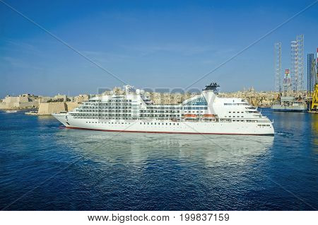 Senglea Malta - June 4 2017: Cruise liner Seabourn Odyssey with Senglea peninsula in a background as seen from Valletta.