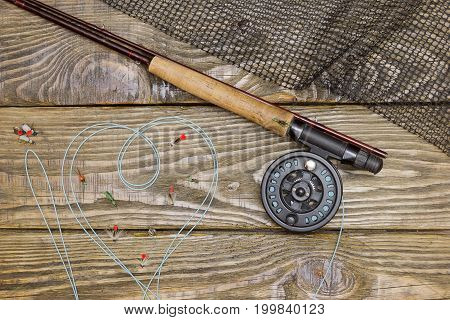 Fly fishing rod , box of flies and a landing net on the old wooden table. All ready for fishing.