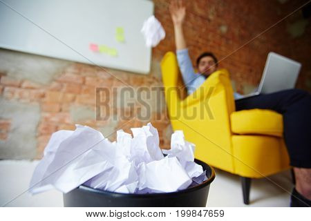 Modern freelancer throwing crumpled paper into trash bin