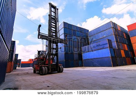 Forklift truck lifting cargo container in shipping yard or dock yard against sunrise sky with cargo container stack in background for transportation importexport and logistic industrial concept