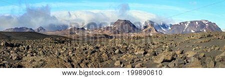 Dramatic volcanic rock desert and mountains of Porisjokull with stormy clouds in sunset light. Icelandic highland near Kaldidalur.