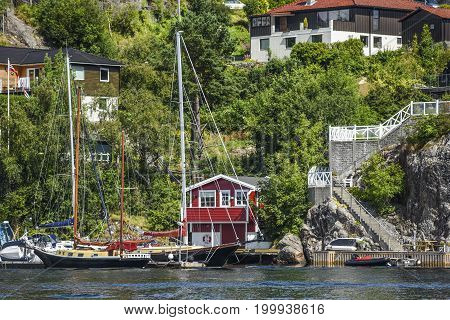 Coast of Norway with yacht and charming cottages in the background summer.