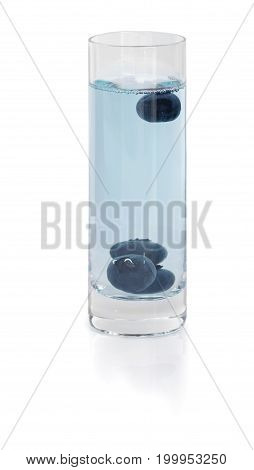 A close-up picture of blueberry shot. An alcoholic drink in a shot glass isolated on a white background. Colorful blue liquor liquid with a few blackberries. Alcoholic cocktails. Copy space.