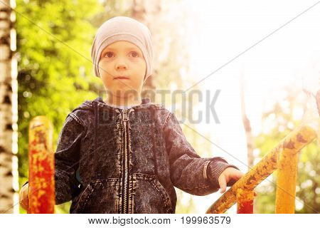 Portrait Of Little Boy On Nature Background Among Birches