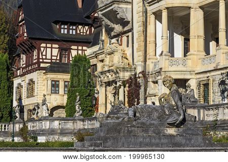 Statue in front of beautiful Peles castle and ornamental garden in Sinaia, Romania, between Valachia and Transylvania