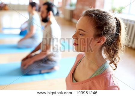 fitness, yoga and healthy lifestyle concept - woman group of people meditating in seated pose at studio