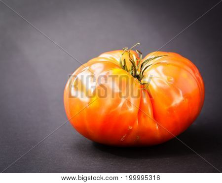Ripe Heirloom Tomato Isolated On Black Back Ground. The tomato is red and ready to be eaten.