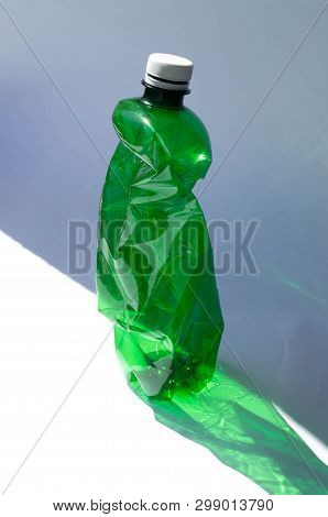 Plastic Green Bottle With A Hard Shadow. The Problem Of Garbage, Recycling And Environmental Polluti