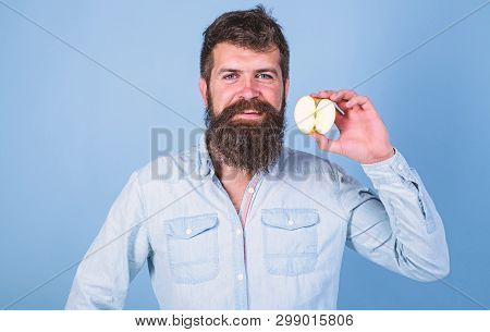 Man Bearded Smiling Holds Apple Blue Background. Half Of Apple Healthy Lifestyle. Nutritional Value 