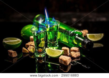 Absinthe Poured Into A Glass. Absinthe Shots With Sugar Cubes. Bottle Of Absinthe And Glasses With B