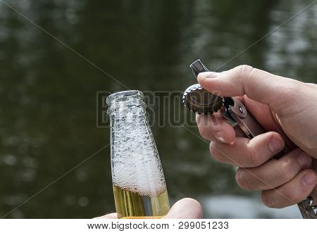 Man Opens A Beer With A Metal Opener In Nature