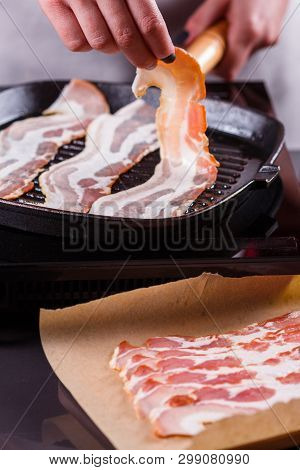 Young Woman In A Gray Apron Fries Bacon