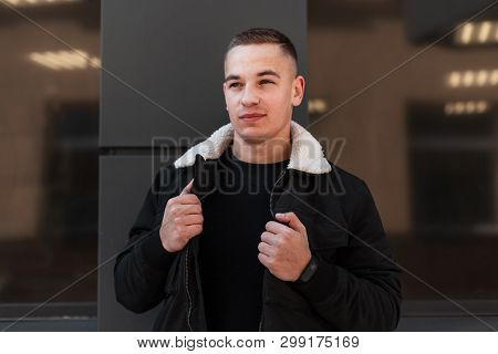 Handsome Attractive Young Man In A Fashionable Black In A Spring Light Jacket Poses Near The Modern