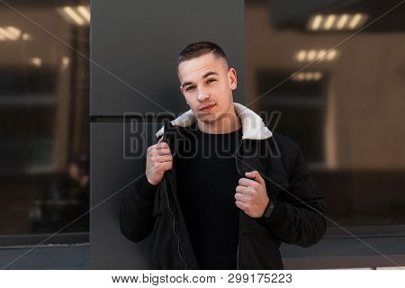 Handsome Attractive Young Man In A Fashionable Black In A Spring Light Jacket Poses Near The Modern 