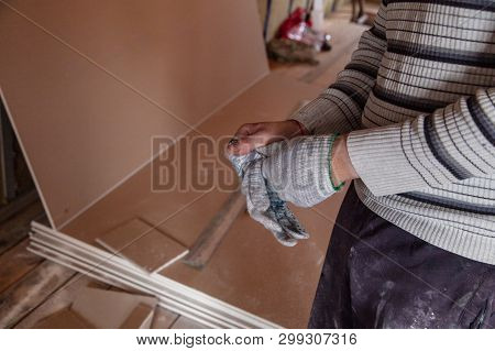 Worker Takes Off Gloves From Hands At A Construction Site.