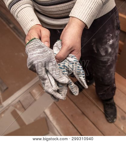 Worker Takes Off Gloves From Hands At A Construction Site.