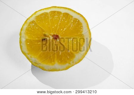 Half A Yellow Lemon With Two Pips On A White Background With A Shaddow Of The Lemon.