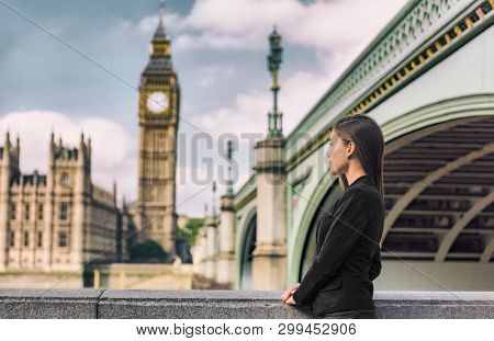 London business people city lifestyle young businesswoman looking at Parliament Big Ben clock tower, UK. Europe politics solicitor or realtor, woman wearing formal black suit for career life.