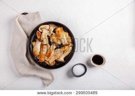 Fried Eryngii Mushrooms In Cast-iron Pan On White Table. Grilled Slices Of King Oyster Mushrooms. To