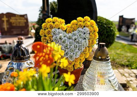 Artificial Flowers In The Shape Of A Heart And Candlesticks Lie On The Tombstone In The Cemetery.