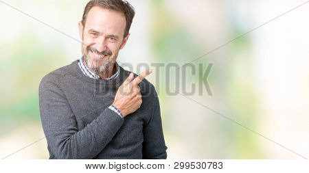 Handsome middle age senior man wearing a sweater over isolated background cheerful with a smile of face pointing with hand and finger up to the side with happy and natural expression on face