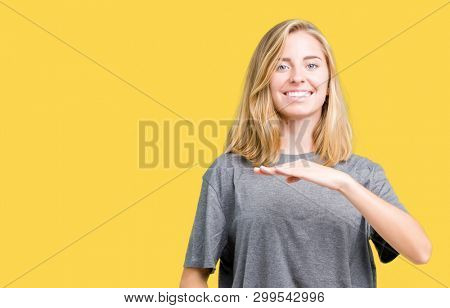 Beautiful young woman wearing oversize casual t-shirt over isolated background gesturing with hands showing big and large size sign, measure symbol. Smiling looking at the camera. Measuring concept.