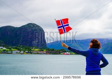 Female Tourist With Norwegian Flag Enjoying Fjord Lysefjord View. National Route Ryfylke. Vacation A