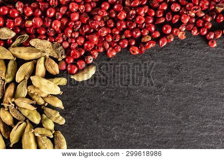 Lot Of Whole True Cardamom Pod And Peruvian Pink Pepper Flatlay On Grey Stone