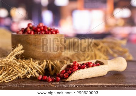 Lot Of Whole Peruvian Pink Pepper In A Wooden Bowl With Wooden Scoop On Jute Cloth In A Restaurant